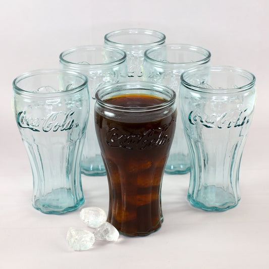 Coca-Cola Gläser Set mit fünf leeren Gläsern und einem gefüllten Glas mit Cola und Eiswürfeln