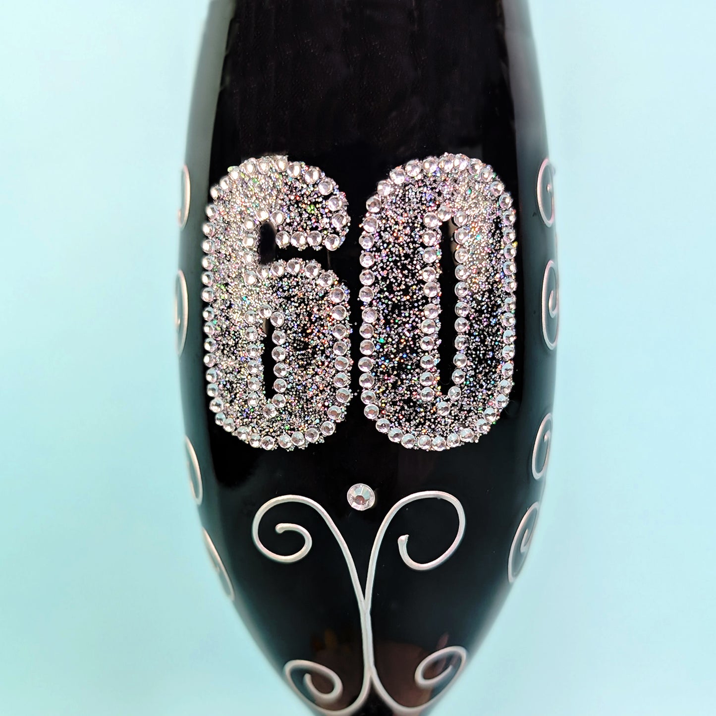 Perspektivische Ansicht des Sektglases mit funkelnder Zahl 60 und Ornamenten