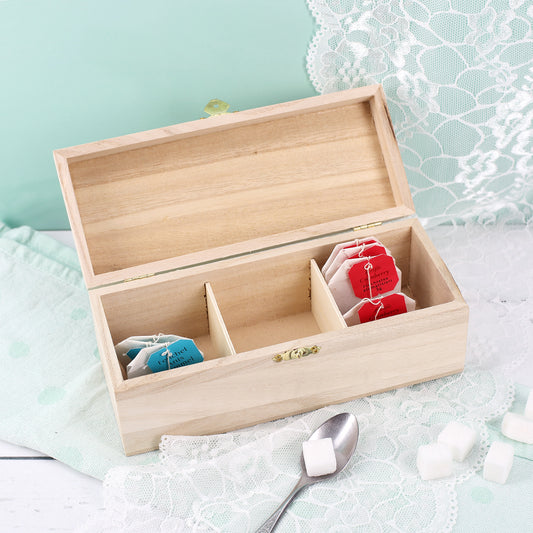 Offene Teebox aus Holz mit drei Fächern, gefüllt mit Teebeuteln, dekorativ arrangiert mit Spitze und Würfelzucker