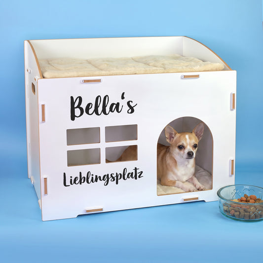 Weißes Katzenhaus mit personalisiertem Namen Bella’s, Wunschtext Lieblingsplatz und kleinem Hund in der Türöffnung