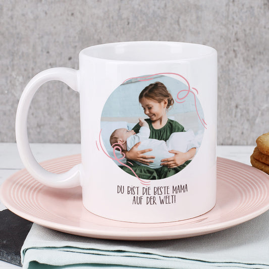 Rückseite der Tasse mit Kinderfoto und Text „Du bist die beste Mama auf der Welt!“ – auf rosa Teller