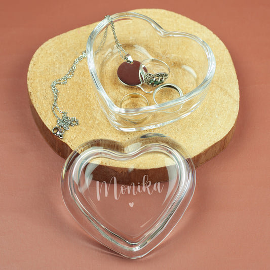 Gravierte Glasdose in Herzform mit Name Monika und Schmuck auf Holzunterlage