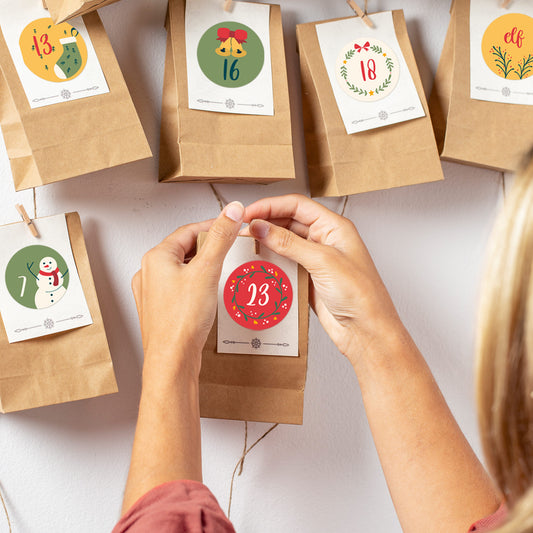 Detailaufnahme: Person bringt den Aufkleber „23“ auf eine Adventstüte an