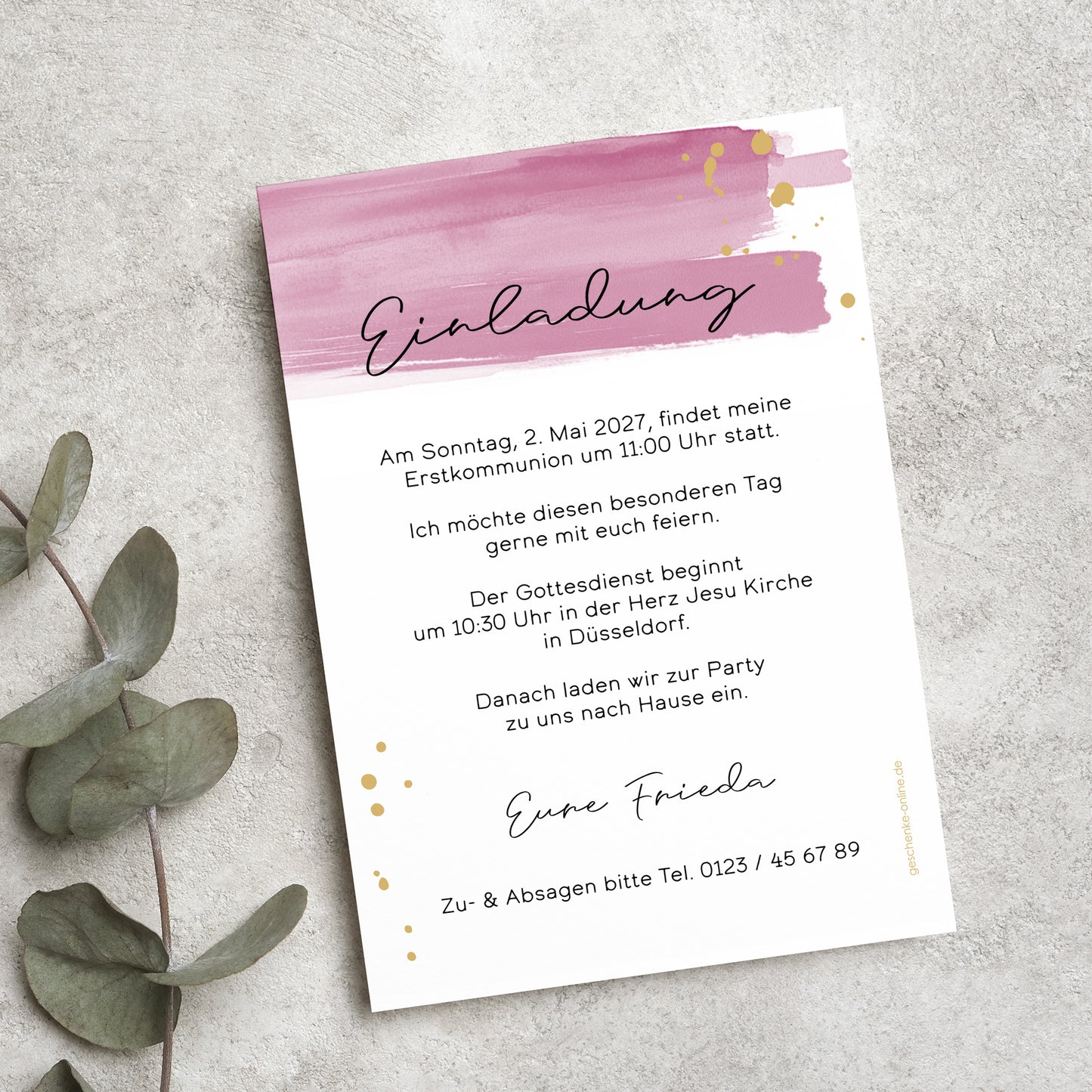 Einladungskarte zur Erstkommunion mit modernem Aquarell-Design in Rosa und goldenen Akzenten. Die Karte ist mit individuellem Einladungstext personalisiert und liegt auf einer Naturstein-Oberfläche, umgeben von Eukalyptusblättern.
