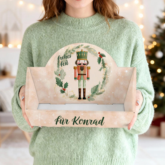 Person hält weihnachtlichen Geschenkkorb mit Nussknacker und Wunschtext