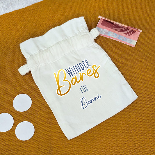 Geldsäckchen mit Aufdruck „WunderBares für Benni“, mit Geldschein auf senfgelbem Untergrund