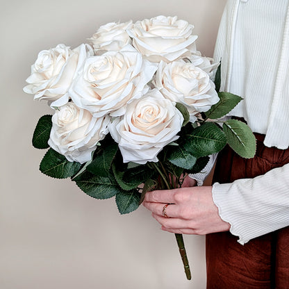 Person hält cremefarbenen Kunstrosenstrauß mit zehn Blüten in der Hand