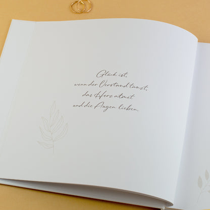 Innenseite Gästebuch Hochzeit mit Zitat „Glück ist …“ und floraler Verzierung