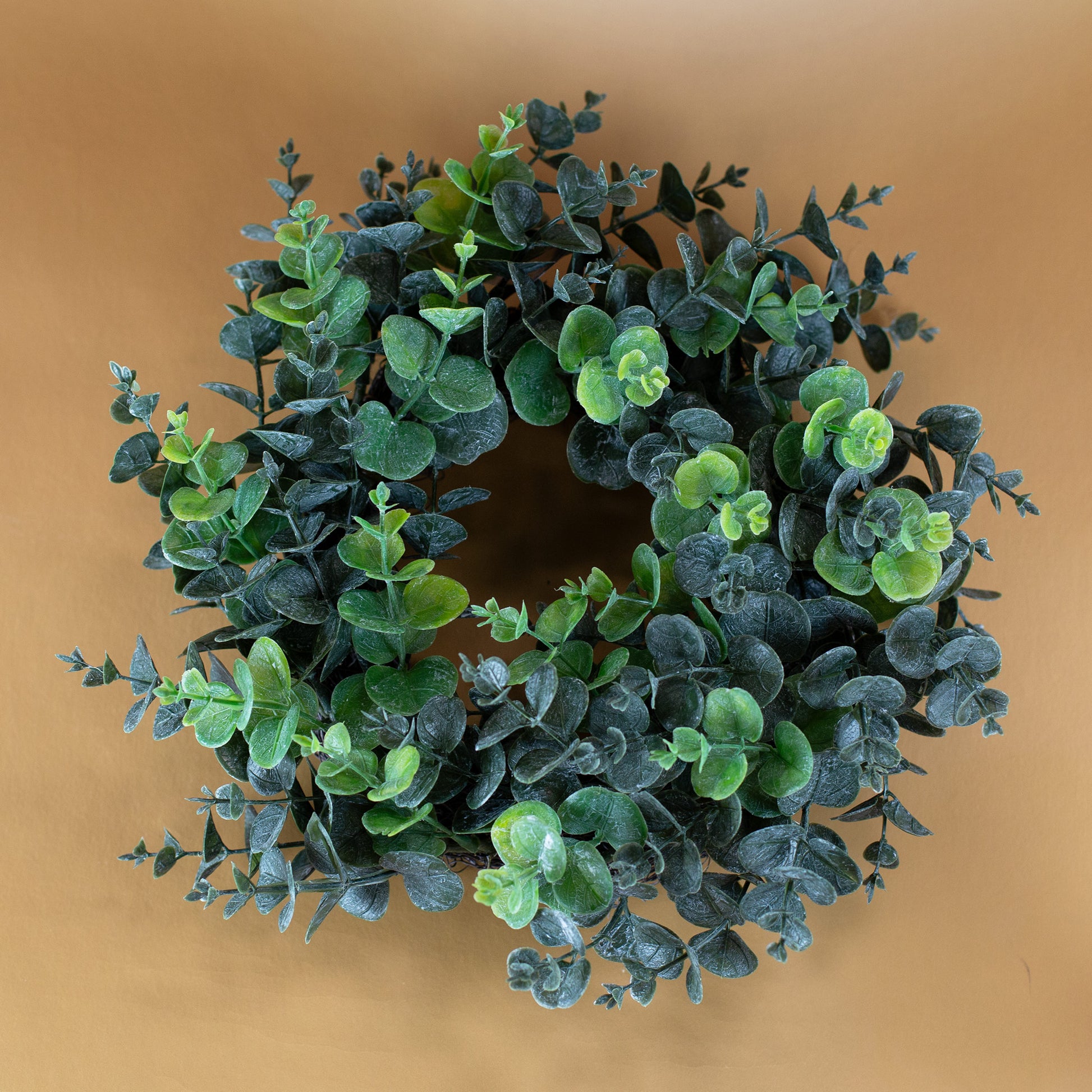 Künstlicher Eukalyptuskranz liegend auf braunem Hintergrund