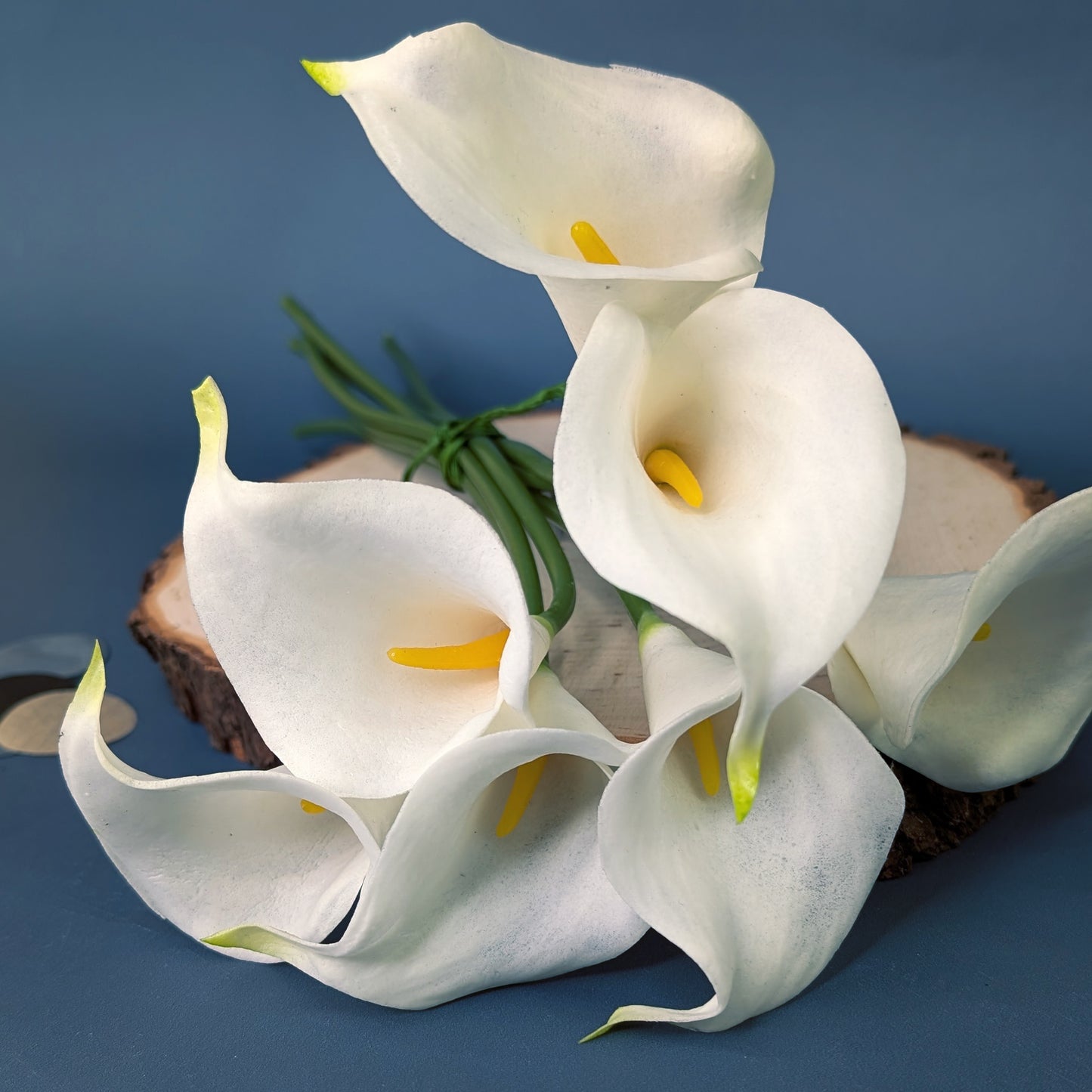 Künstlicher Calla-Strauß aus sieben Blüten auf Holzscheibe dekoriert