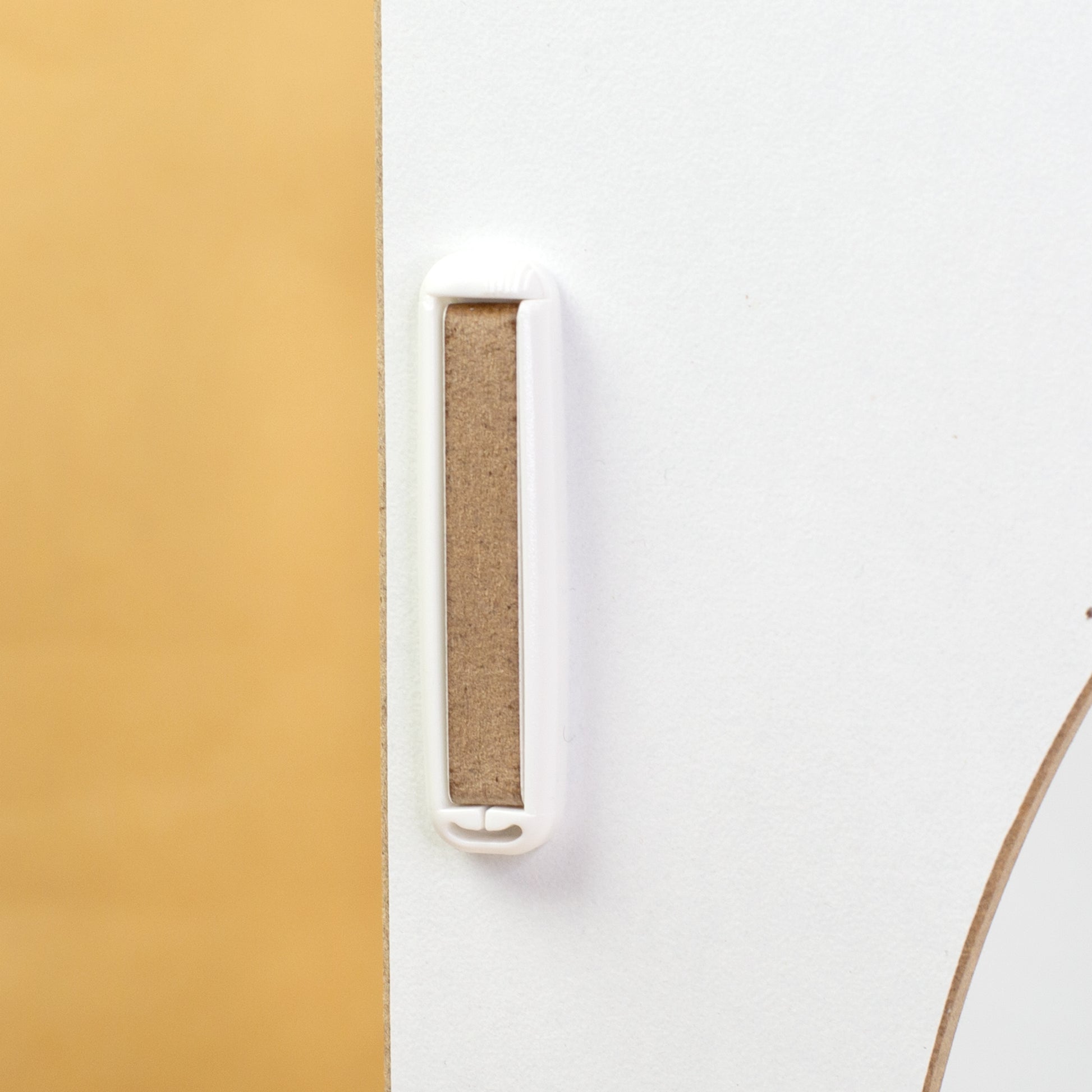 Detailaufnahme der weißen clipfritz Klammer an einem weißen MDF-Element des KALLAX Einsatzes