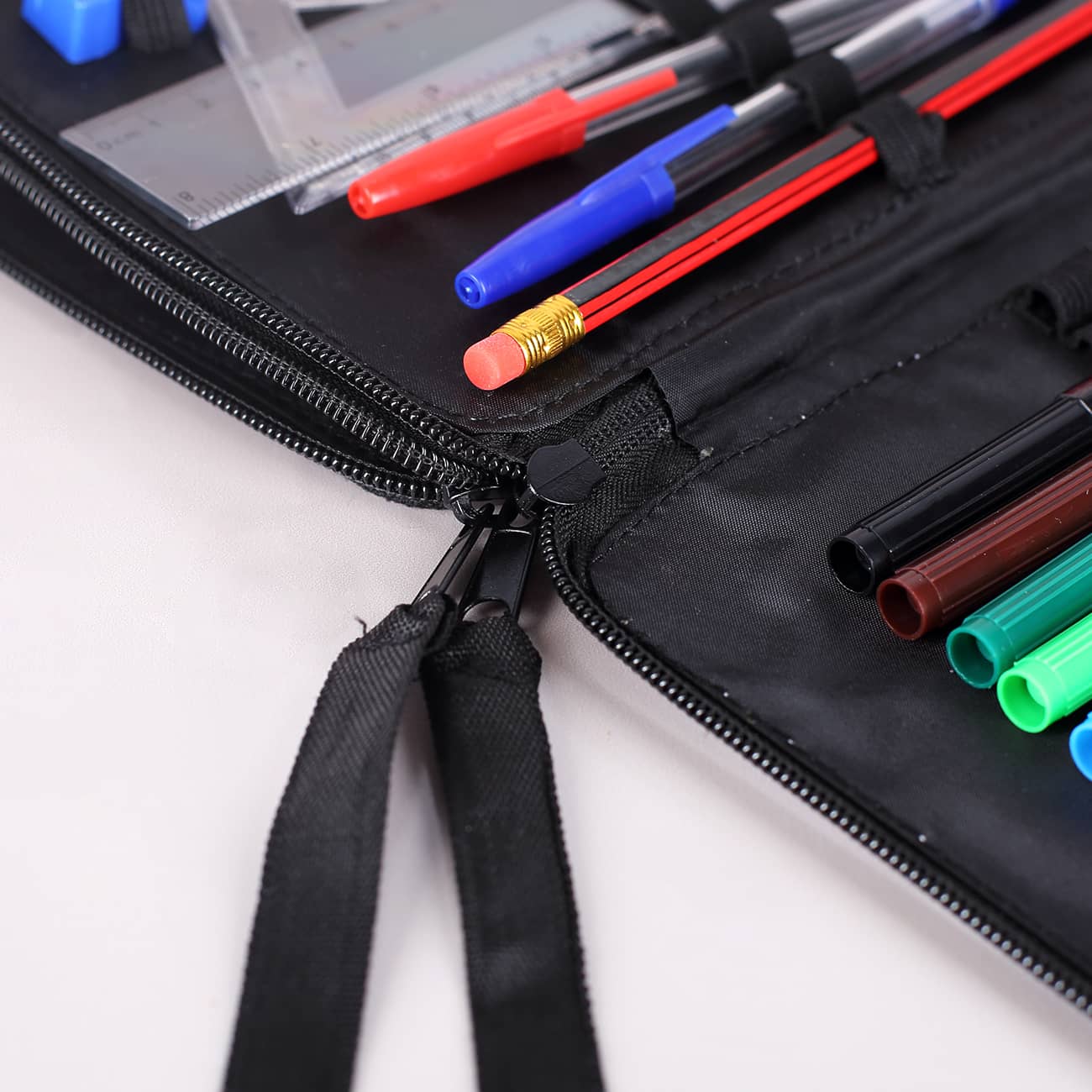 Detailaufnahme des Reißverschlusses und der Federmappen-Fächer mit Stiften und Zubehör.