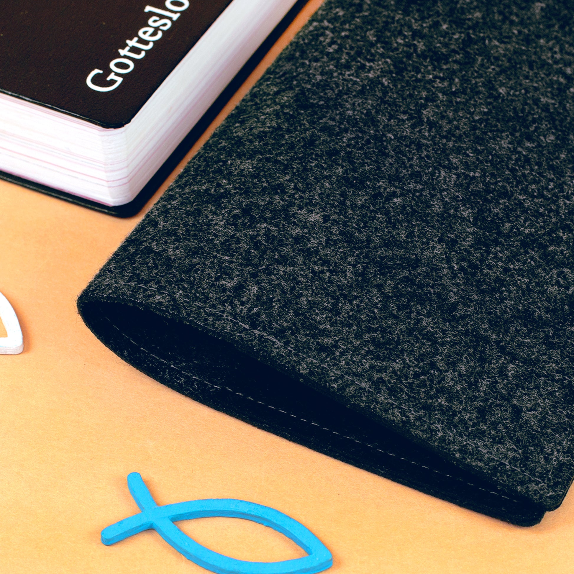 Nahaufnahme der anthrazitfarbenen Filz-Buchhülle mit Materialstruktur und Fisch-Dekoration
