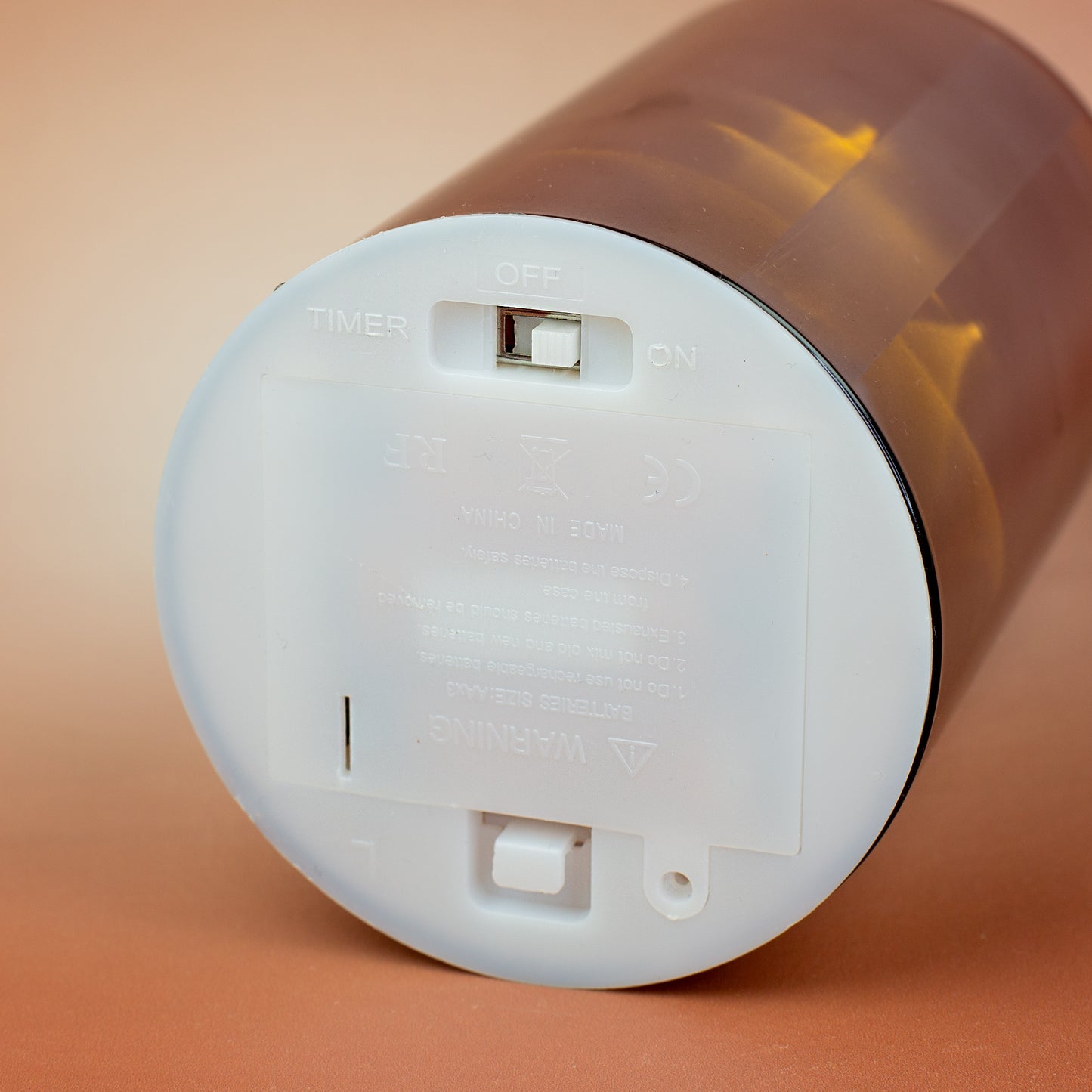 Detailaufnahme der Unterseite der Leonardo LED-Glaskerze mit Ein/Aus/Timer-Schalter und Batteriefach für drei AA-Batterien.