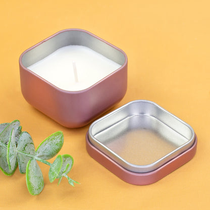 Roségoldene Mini Duftkerze mit geöffnetem Deckel und weißem Wachs auf gelbem Hintergrund mit Eukalyptus Deko