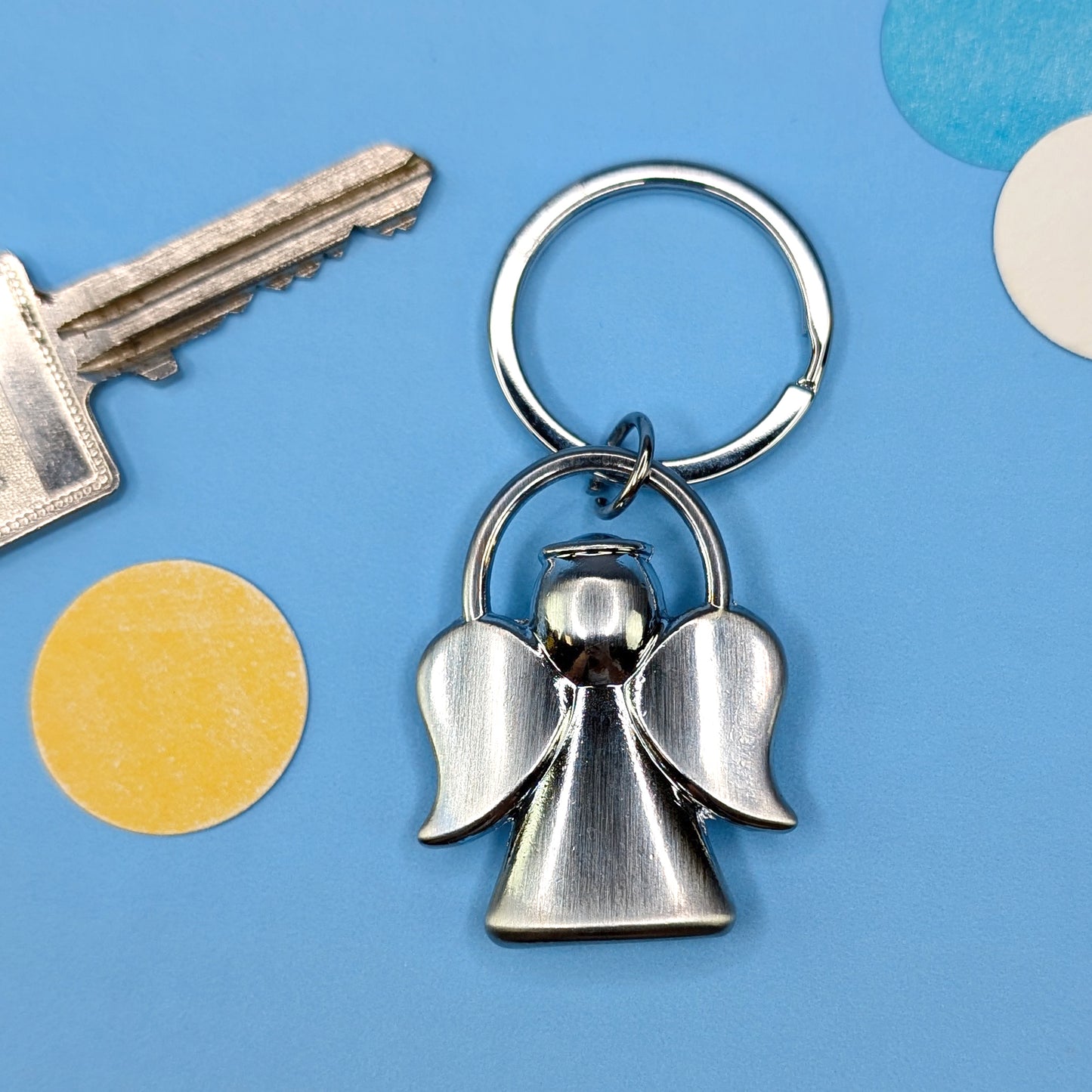 Rückansicht des Schutzengel-Schlüsselanhängers aus Metall, vor blauem Hintergrund