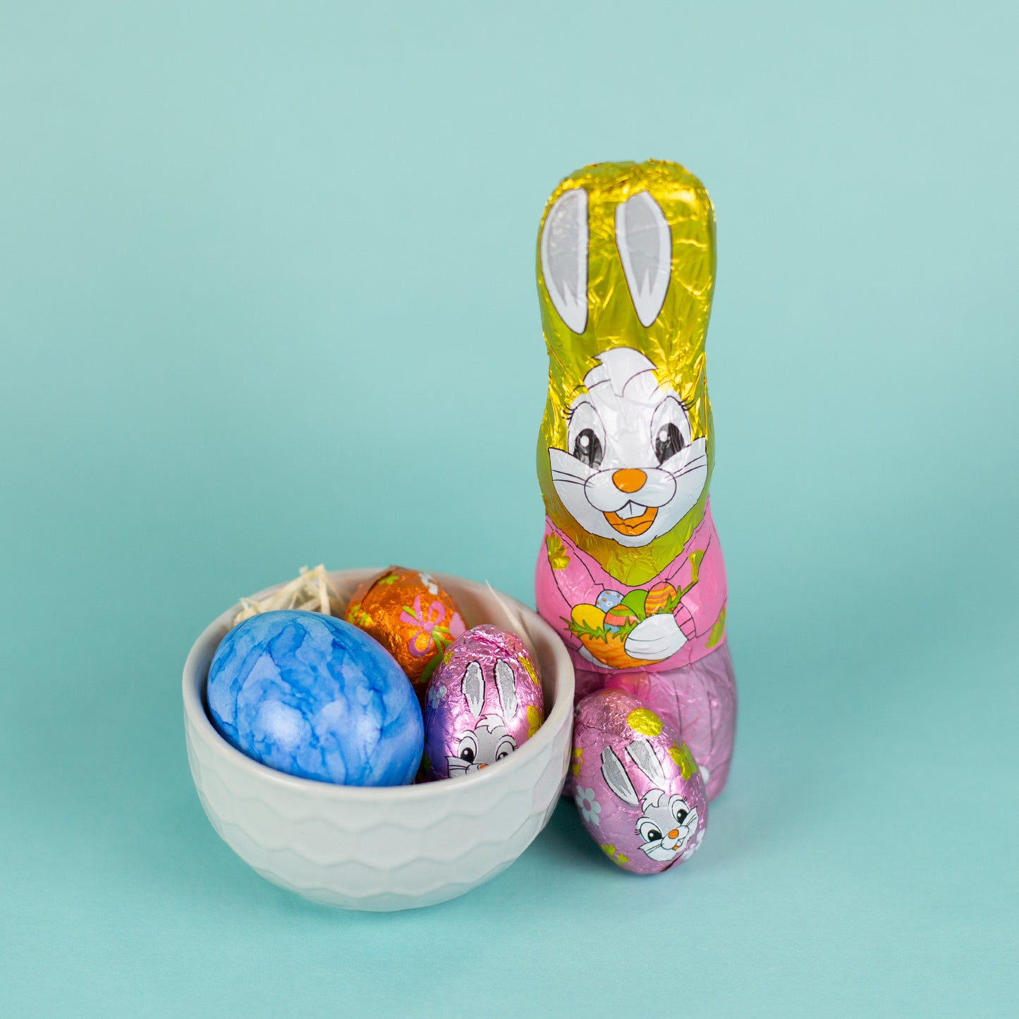 Riegelein Oster-Mischbeutel 100g ausgepackt stehend neben einem grauen Becher aus Keramik mit Holzwolle