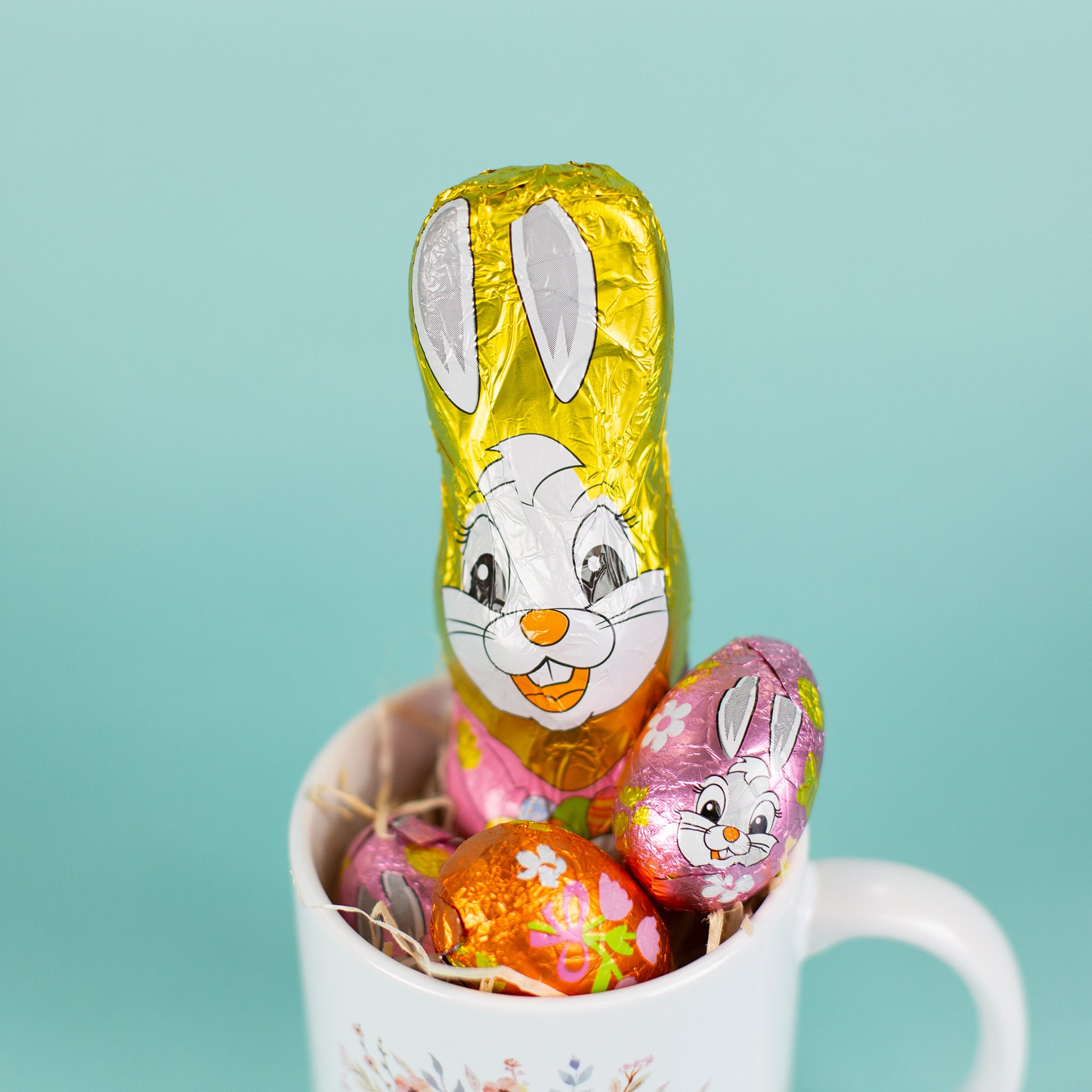 Nahaufnahme des Riegelein Oster-Mischbeutel 100g ausgepackt in einer Tasse zusammen mit Holzwolle