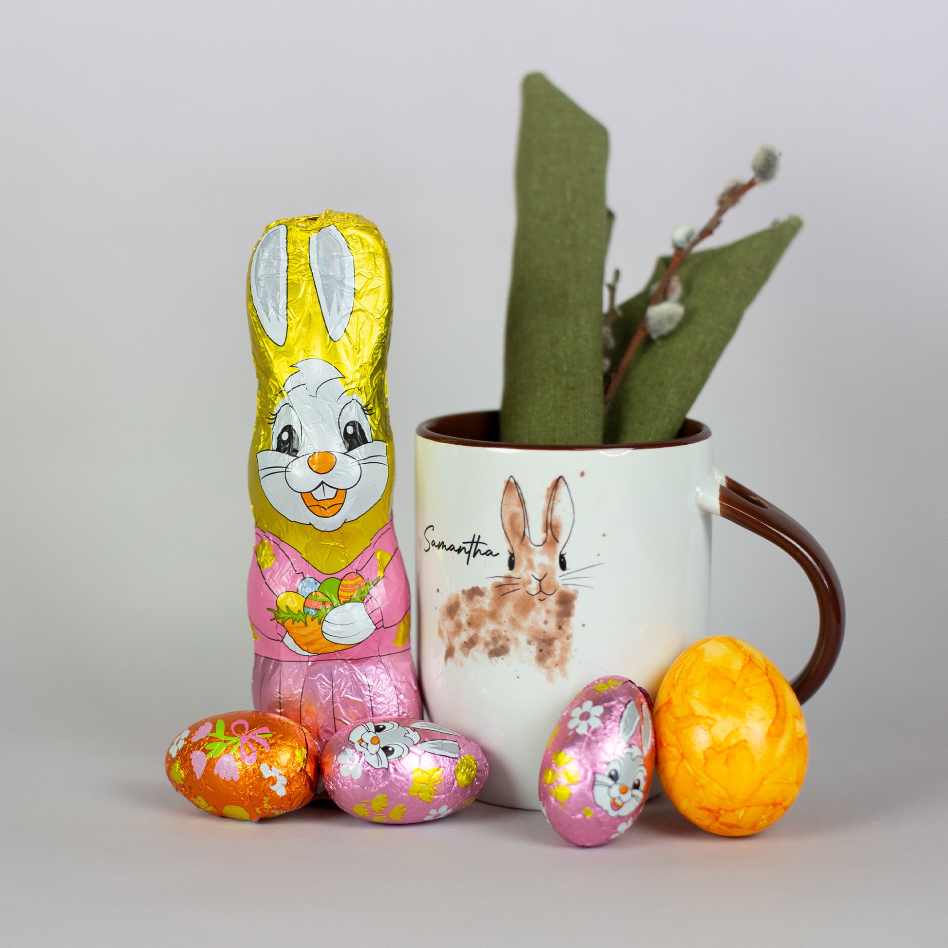 Riegelein Oster-Mischbeutel 100g ausgepackt stehend neben einer Tasse mit Oster-Motiv