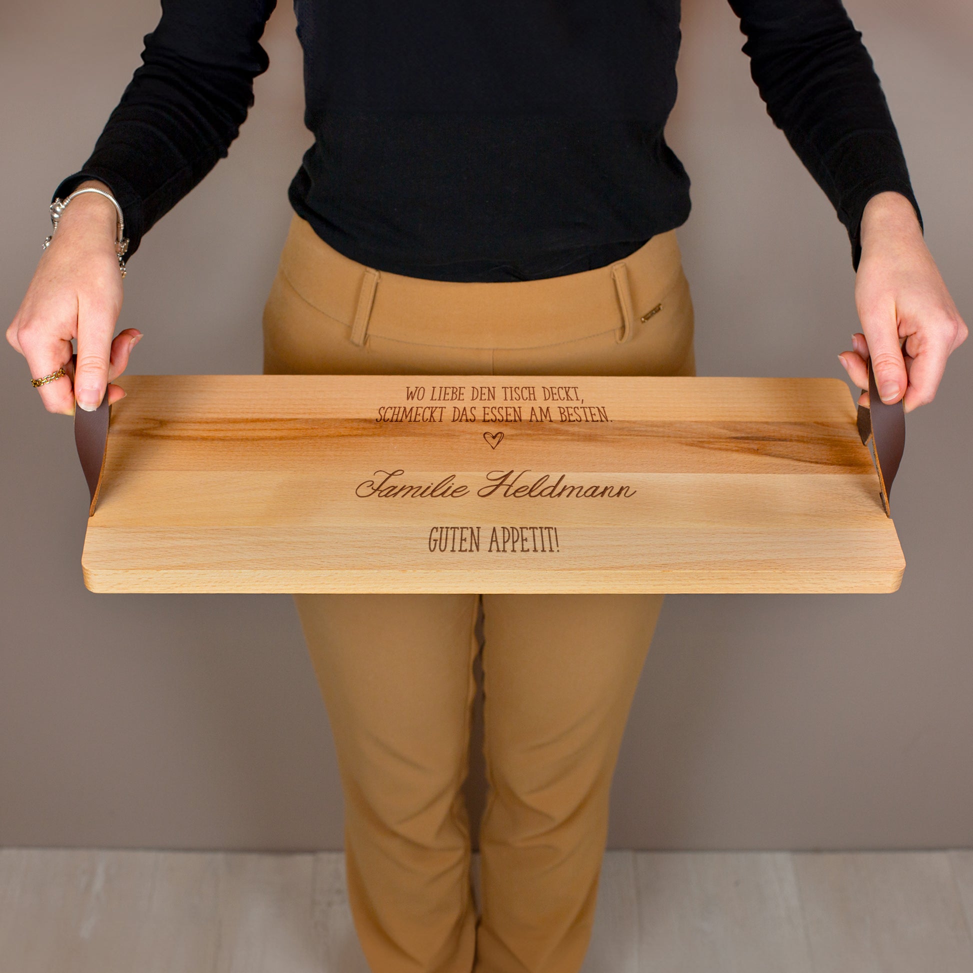 Person hält Servierbrett aus Buchenholz mit Ledergriffen und personalisierter Gravur