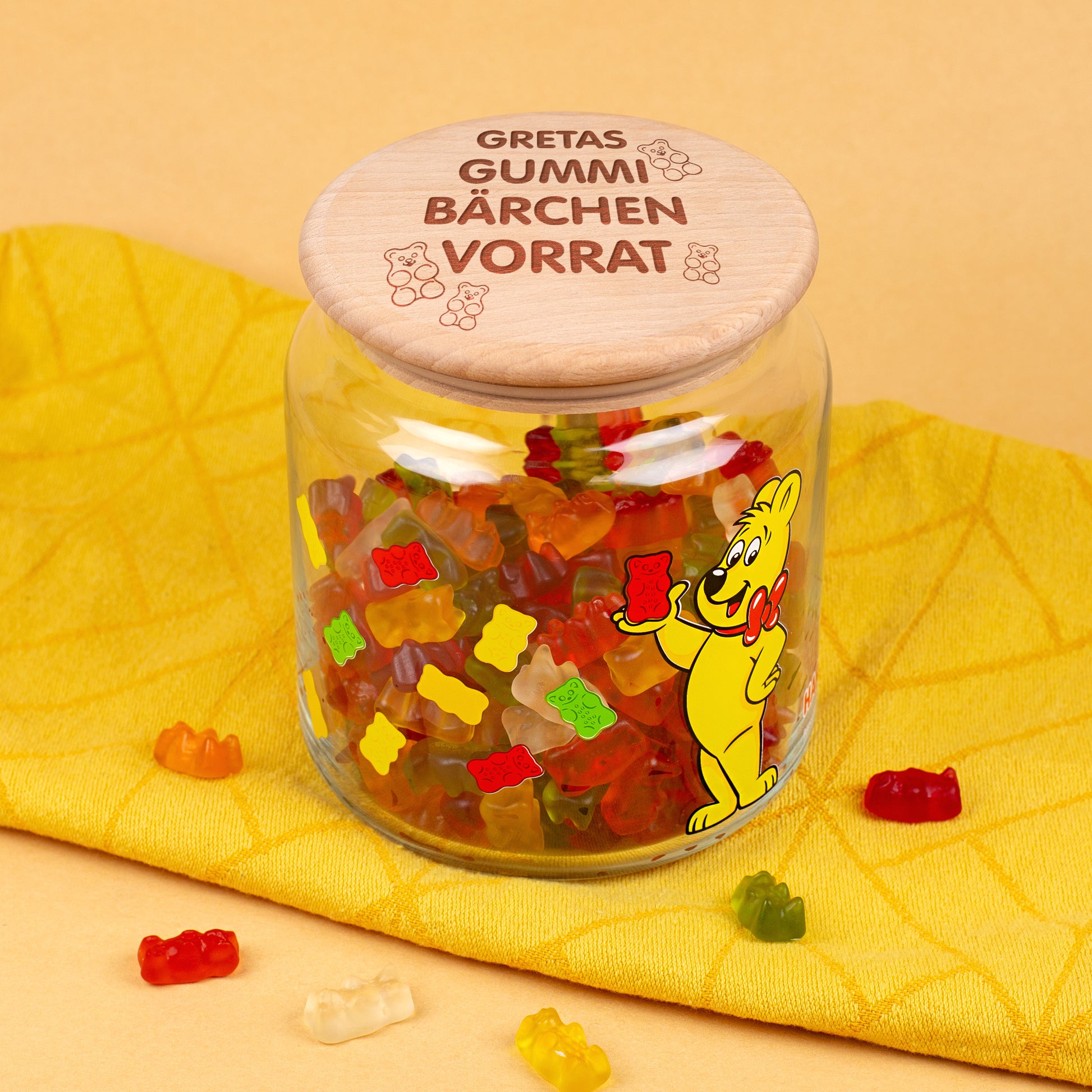 HARIBO Glasdose mit Goldbär-Aufdruck und graviertem Deckel auf gelbem Hintergrund.