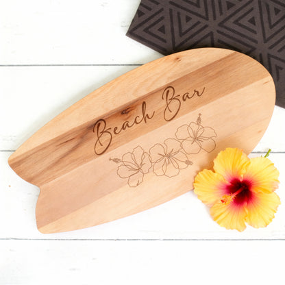 Surfbrett-Servierbrett aus Holz mit Hibiskusgravur und gelber Blüte als sommerliche Dekoration
