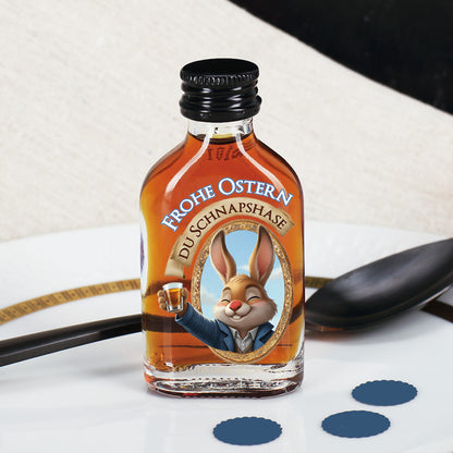 Mini Likörflasche mit Kräuterlikör und Osterhasenmotiv „Frohe Ostern Du Schnapshase“ auf weißem Teller dekoriert