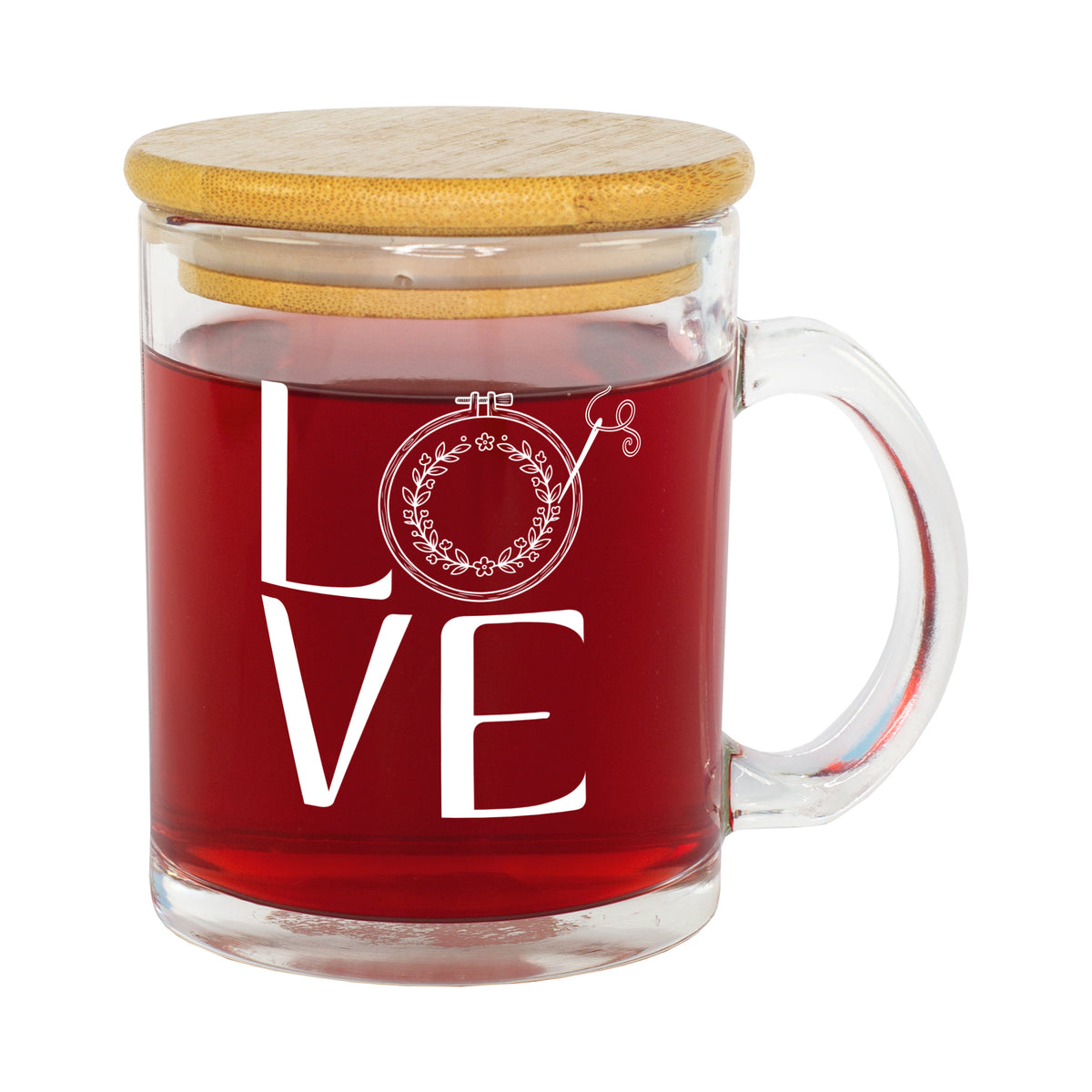 Freigestellte Glastasse mit rotem Tee, weißem LOVE Stickmotiv und Bambusdeckel