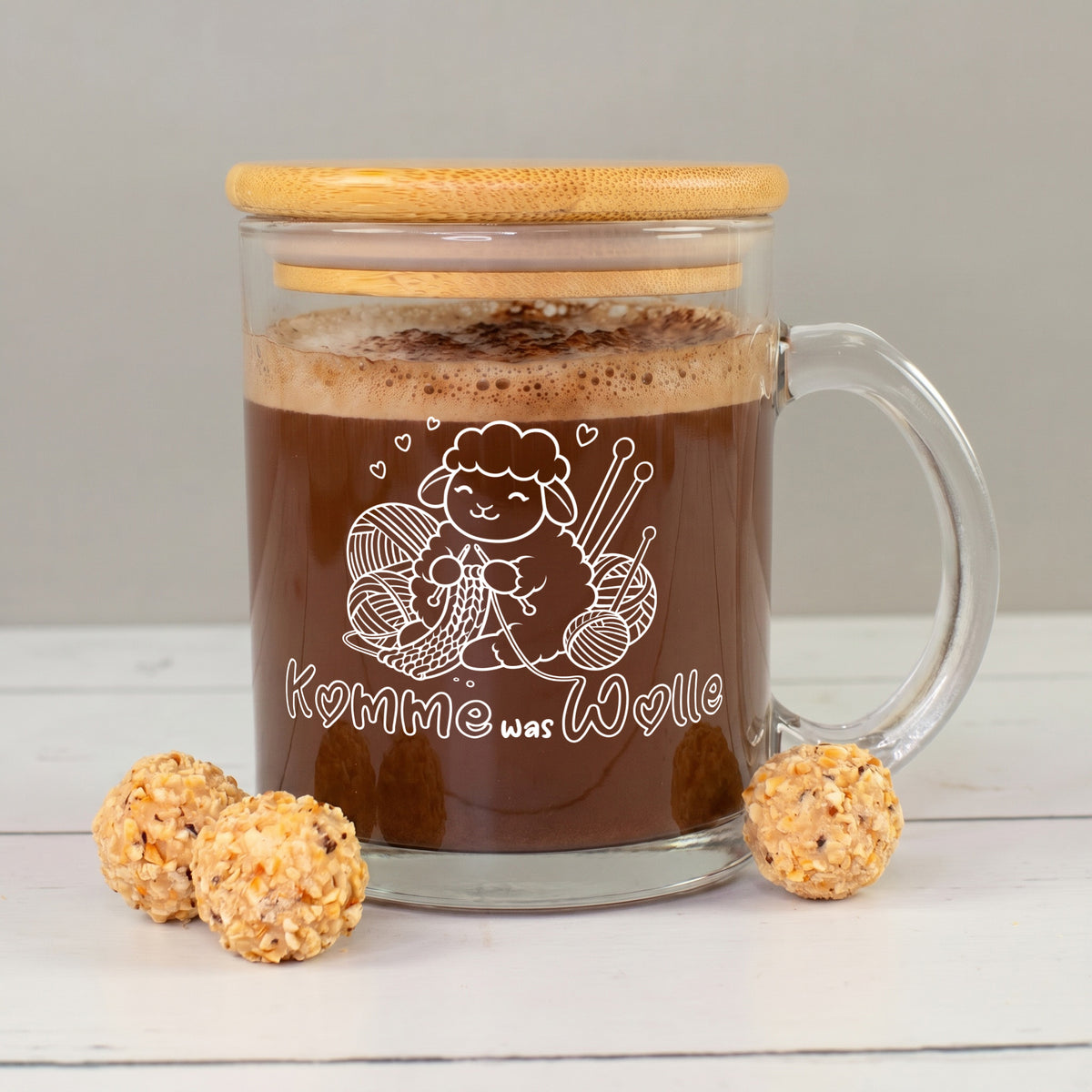 Glastasse mit Bambusdeckel, Kakao und weißem Schaf-Strickmotiv „Komme was Wolle“ mit Wollknäueln