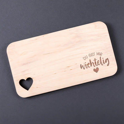 Holzbrettchen mit Spruch „Du bist mir wichtelig“ und Herzmotiv vor dunklem Hintergrund.
