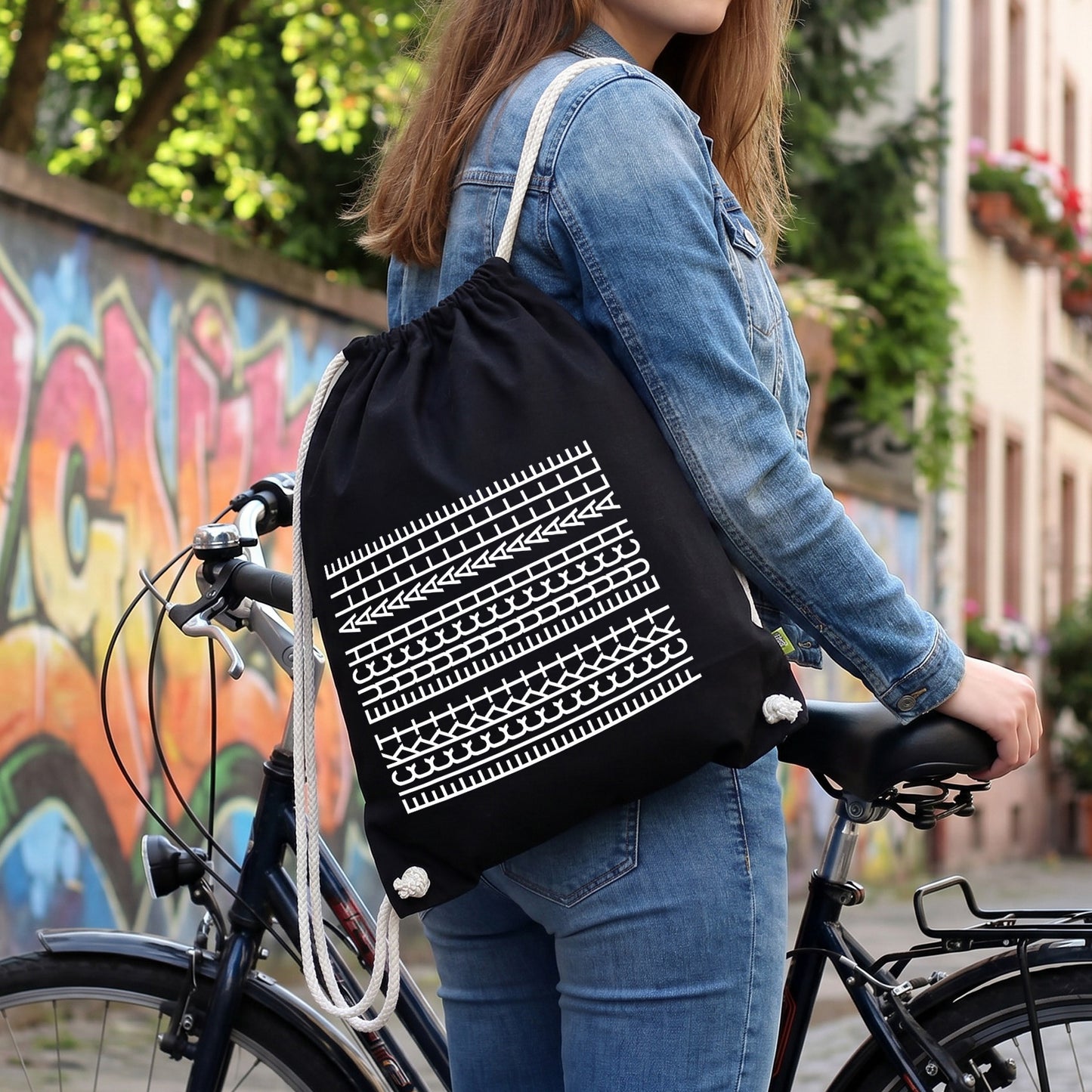 Schwarzer Turnbeutel mit weißem Muster-Motiv „F*ckt euch alle“ als Freizeitrucksack am Fahrrad getragen