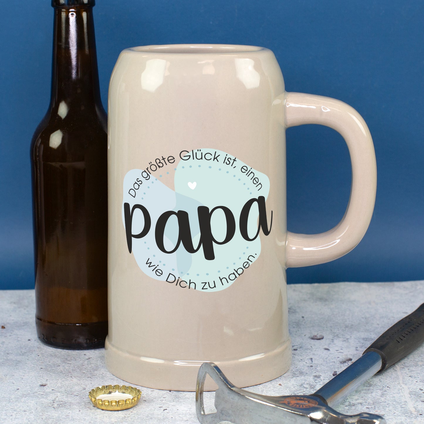 Großer Keramik Bierkrug mit Papa-Spruch neben Bierflasche und Werkzeug als Vatertagsgeschenk