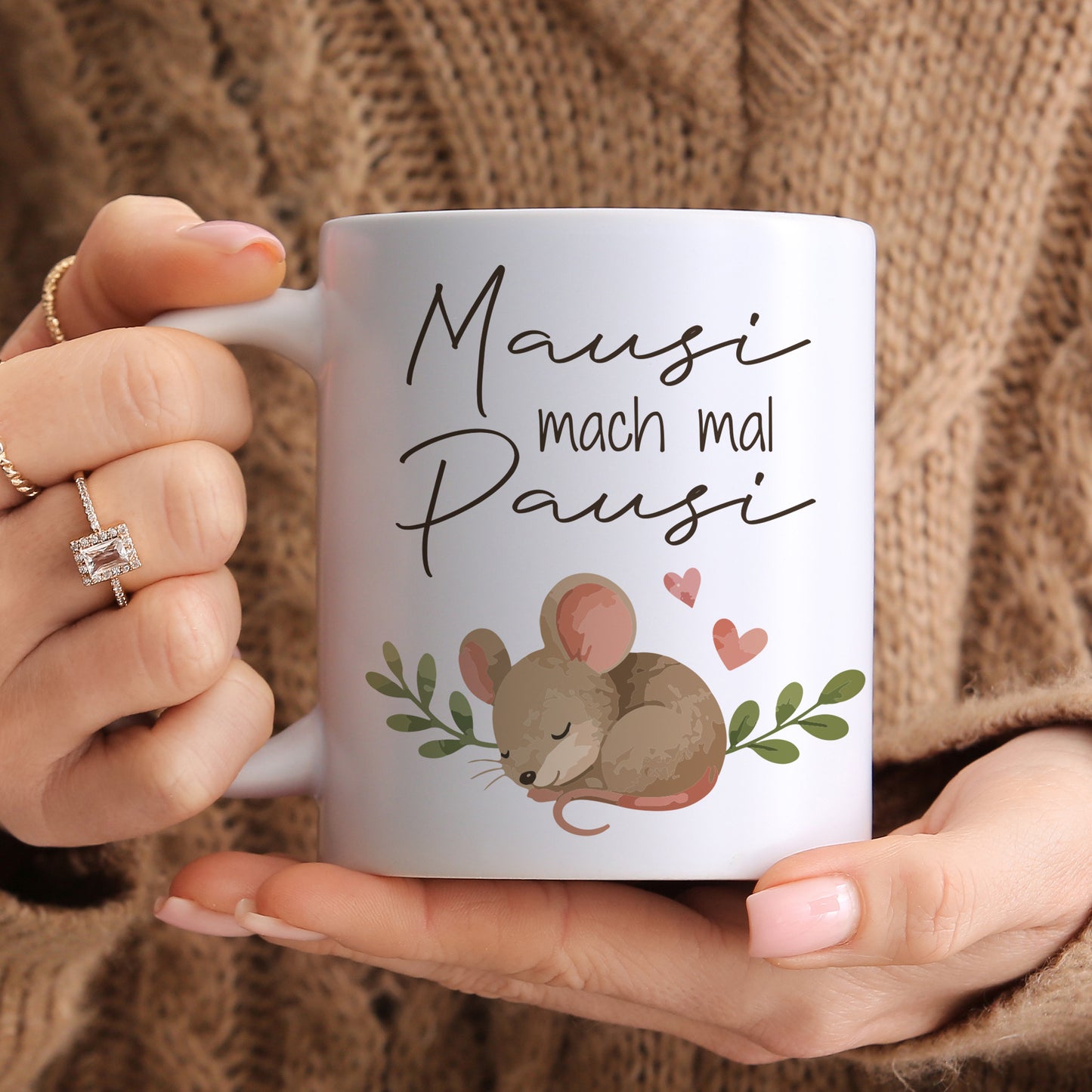 Weiße Keramiktasse mit Spruch Mausi mach mal Pausi und Maus Motiv in den Händen gehalten