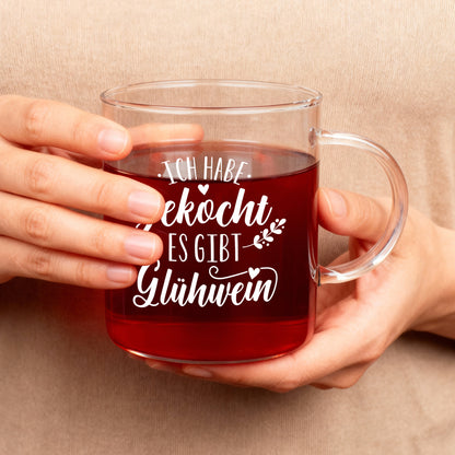 Person hält LEONARDO-Glühweinglas mit weißem Schriftzug und rotem Getränk in beiden Händen.