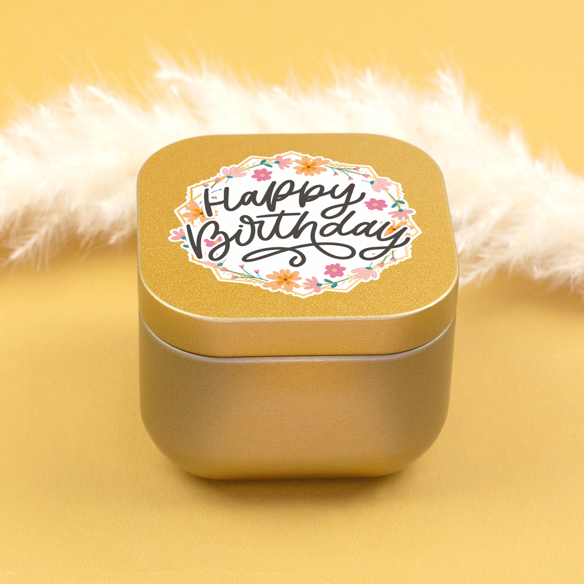 Geschlossene goldene Mini Duftkerze mit floralem Happy Birthday Motiv auf gelbem Hintergrund