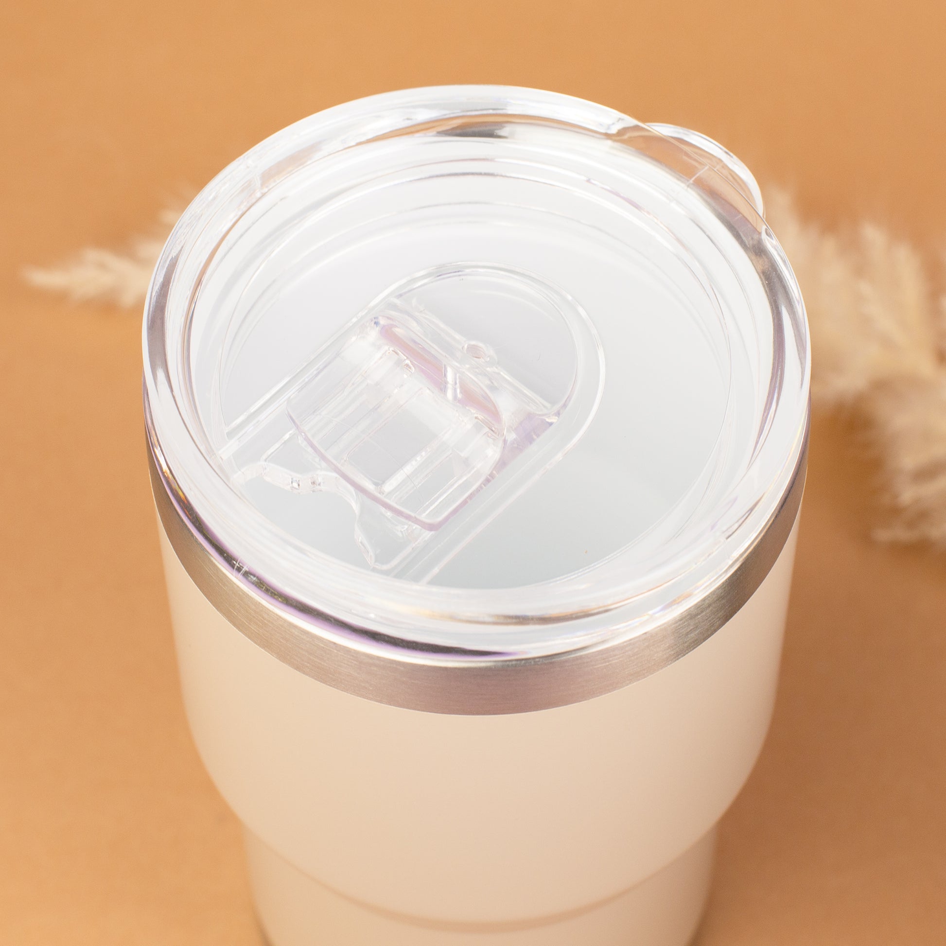 Draufsicht auf beigen Thermobecher mit transparentem Deckel und Trinköffnung
