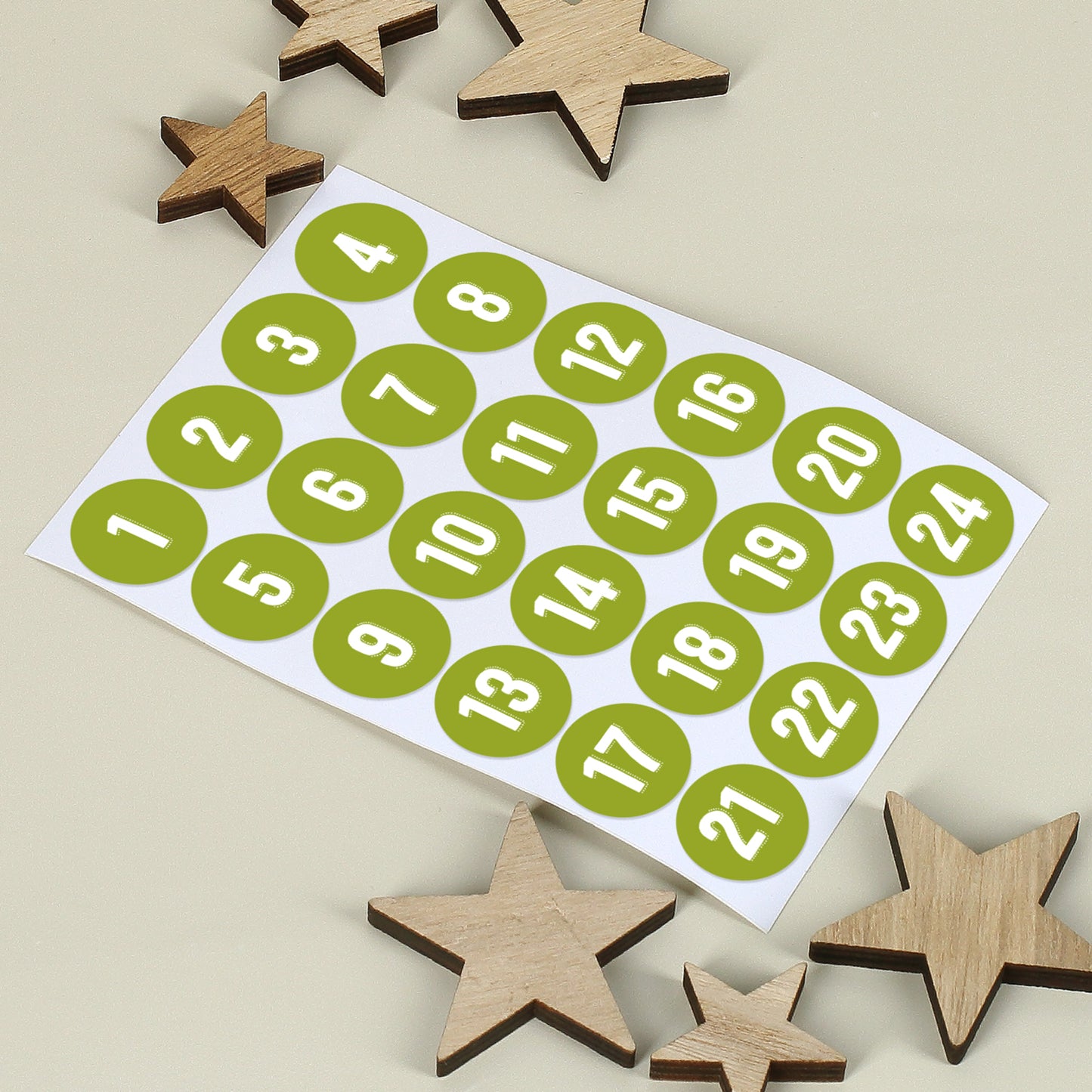 Bogen mit 24 nummerierten Aufklebern in Grün, daneben kleine Holzsterne auf hellem Hintergrund
