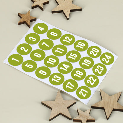 Bogen mit 24 nummerierten Aufklebern in Grün, daneben kleine Holzsterne auf hellem Hintergrund