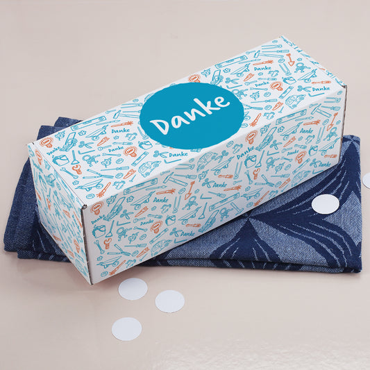 Geschenkverpackung mit Werkzeug-Motiv und großem blauen Danke-Kreis von schräg oben fotografiert