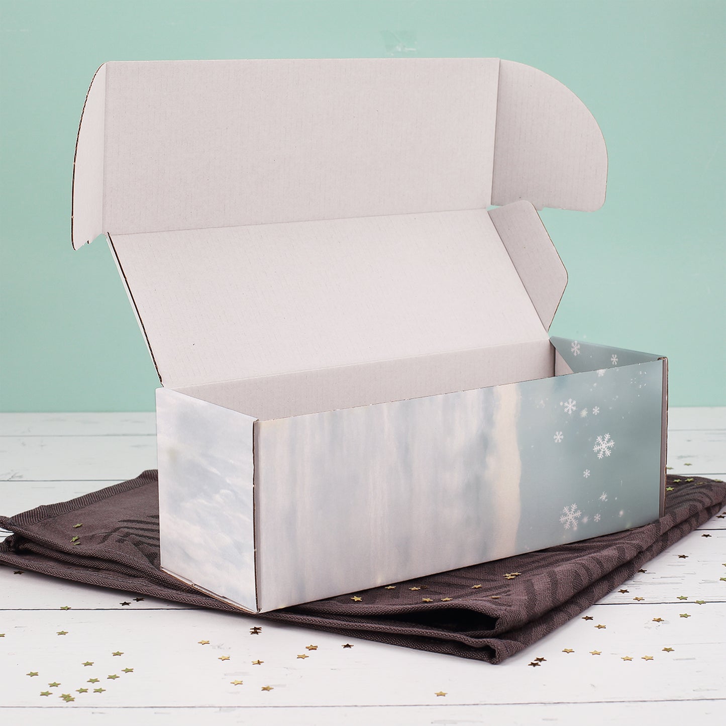 Geöffnete Flaschenverpackung mit winterlichem Wichtelmotiv, liegend auf dunklem Tuch