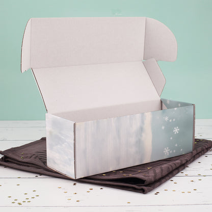 Geöffnete Flaschenverpackung mit winterlichem Wichtelmotiv, liegend auf dunklem Tuch