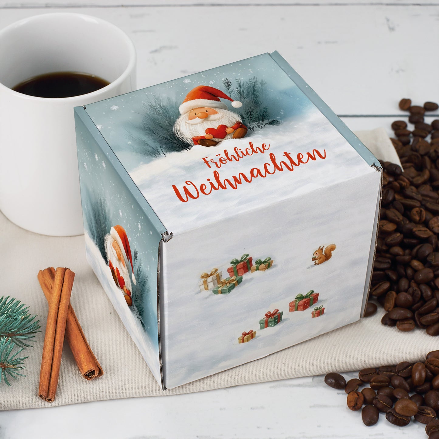 Quadratische Weihnachts-Geschenkbox mit Wichtelmotiv – Box neben Kaffeetasse und Zimtstangen