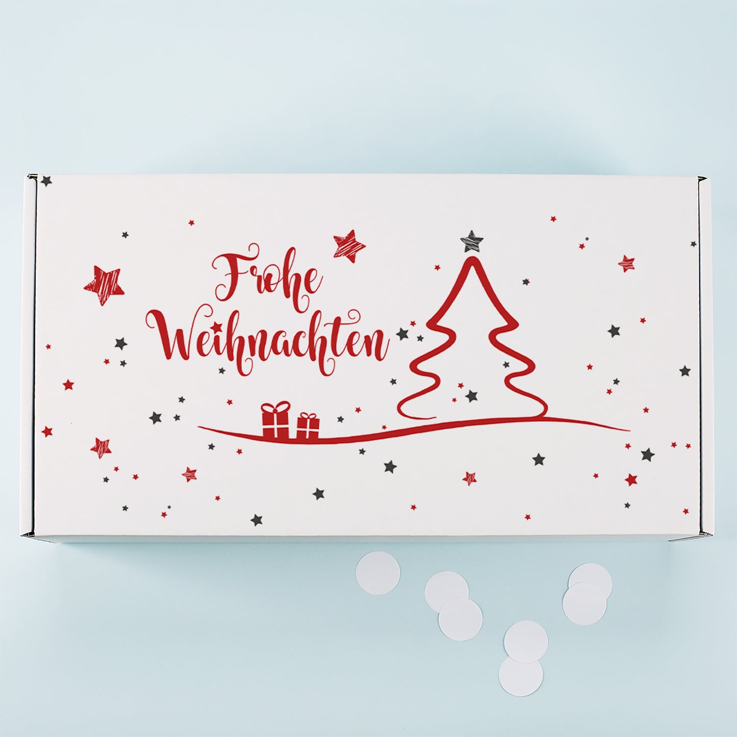 Weiße Geschenkbox von oben mit rotem Weihnachtsbaum Motiv, Geschenken, Sternen und Frohe Weihnachten Schriftzug