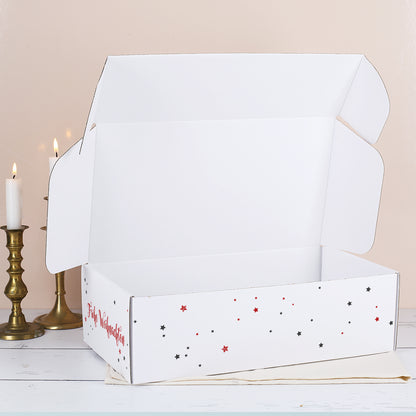 Geöffnete weiße Weihnachtsbox mit rotem und schwarzem Sternenmuster sowie schlichtem weißem Innenraum