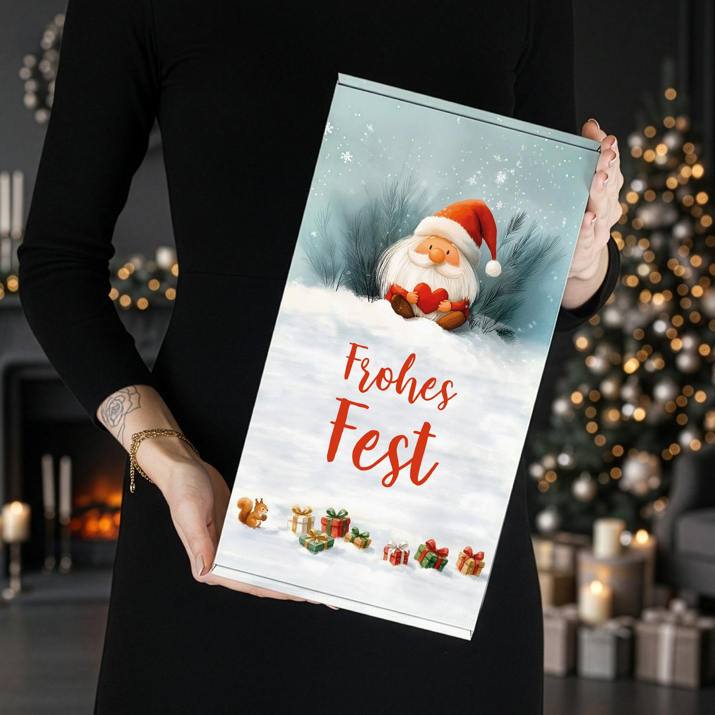 Person hält große Geschenkbox mit winterlichem Wichtelmotiv und Aufdruck „Frohes Fest“