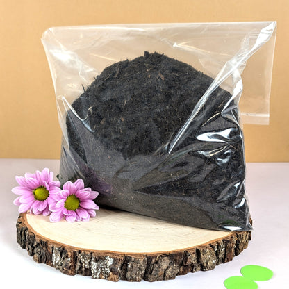 Beutel mit Pflanzerde auf Holzscheibe mit Blüten dekoriert