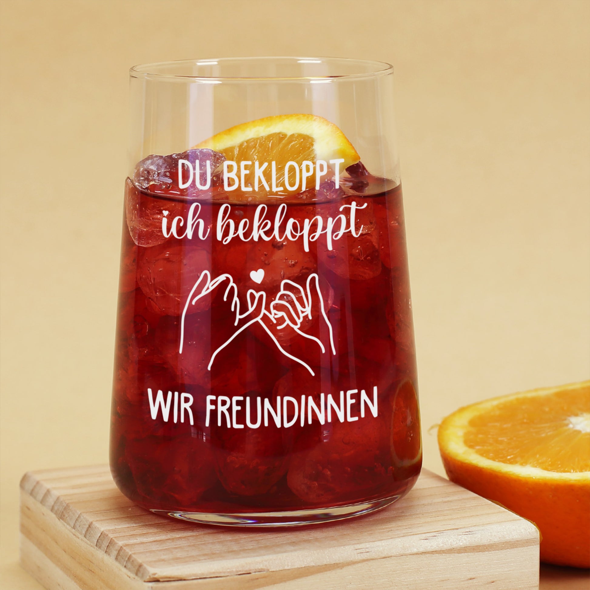 Trinkglas mit rotem Getränk, Eiswürfeln, Orangenscheibe und witzigem Spruch für Freundinnen