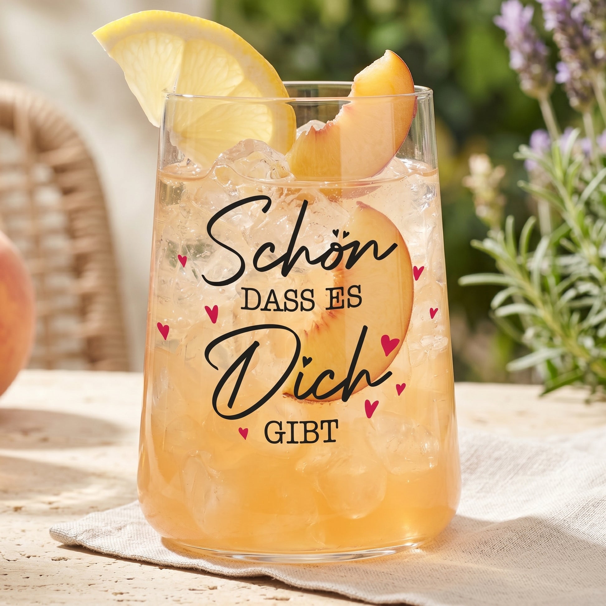 Trinkglas mit Pfirsichgetränk, Eiswürfeln, Zitrone und liebevollem Herz-Aufdruck