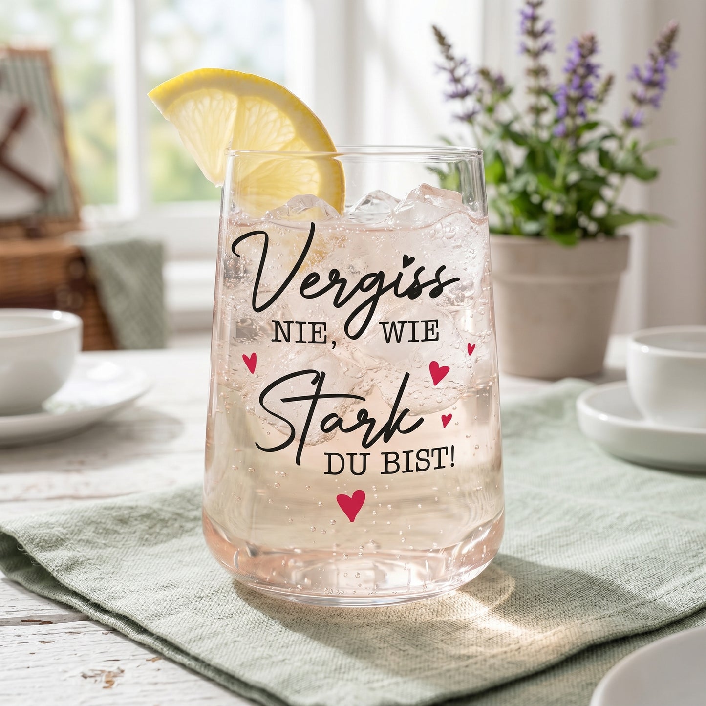 Trinkglas mit Aufdruck Vergiss nie wie stark du bist und Zitronenscheibe auf Küchentisch