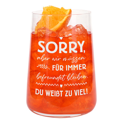 Trinkglas mit orangefarbenem Getränk, Eiswürfeln und weißem Freundinnen-Spruch auf weißem Hintergrund